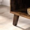 Detalje af rustikt TV-skab med træben og mørk træoverflade.
