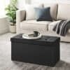 Sort foldbar ottoman med opbevaringsboks i stue med sofa.