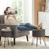 Person læser avis på komfortabel sofa med fodstøtte i stue.