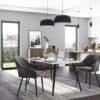 Elegant spisestue med polstret stol, sort design, moderne belysning og naturligt lys.
