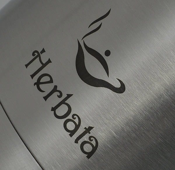 Herbalata logo på metaloverflade, fokus på branding og design.