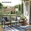 Balkon med to sorte loungestole, sidebord og grønne planter i baggrunden.
