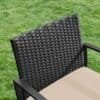 Sort polyrattan balkonstol med beige siddeplade på græs.