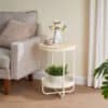 Stue med sidebord, blomster og sofa i lys farvetone.