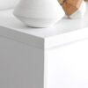Hvidt bord med keramisk vase og geometrisk trædekoration.