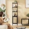 Elegant sort metalbogreol med rattan-lignende dør i stue.