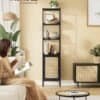 Elegant sort metalbogreol med rattan-lignende dør i stue.