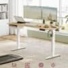 Elektrisk skrivebord med dualskærm, laptop, og tilbehør i lyst hjemmekontor.
