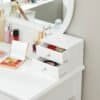 Hvid makeup-kommode med to åbne skuffer og makeupprodukter.