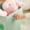 Blød pink bamse i grøn opbevaringsboks til børneværelse.