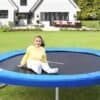 Smilende pige på trampolinen i den grønne have.