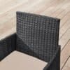 Sort polyrattan balkonstol med beige pude på træterrasse.
